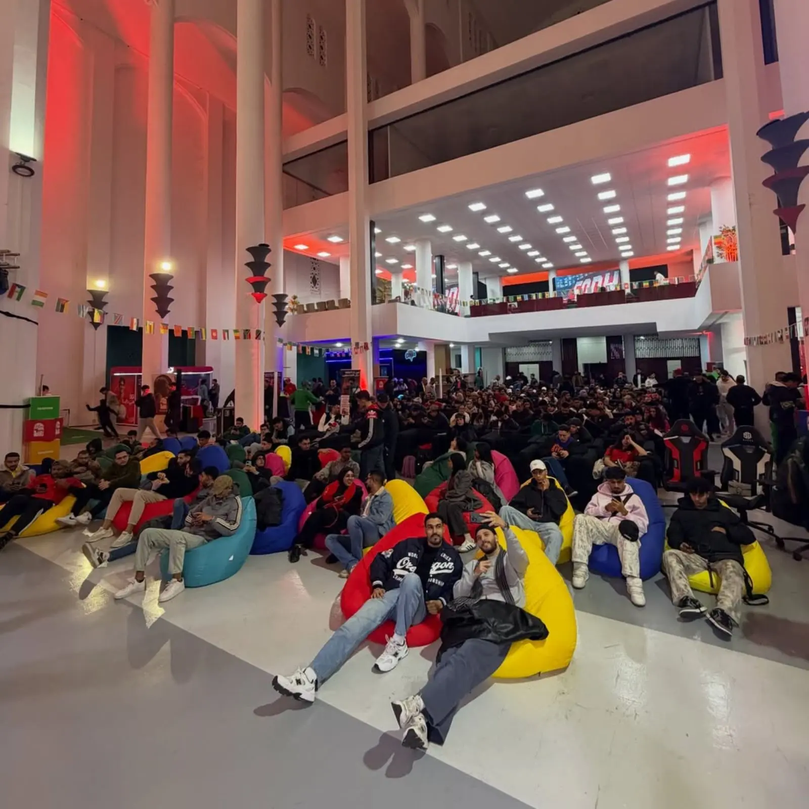 Espace jeunes de la Fanzone Ezone lors de la CAN 2025 à Casablanca, zone de retransmission des matchs avec poufs colorés, public jeune rassemblé pour suivre un match du Maroc, aménagement événementiel réalisé par MG Corp.